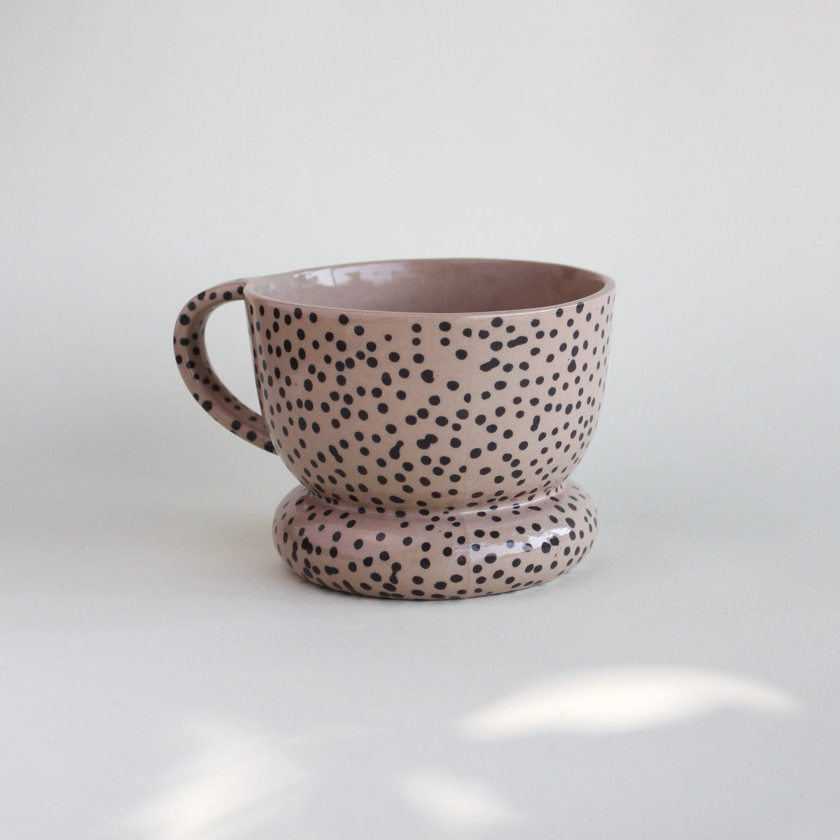 Ceramiczny kubek OJ Kropki z kamionki z recyklingu, różowawy z czarnymi kropkami naniesionymi w masie, ręcznie robiony w pracowni Tokiart